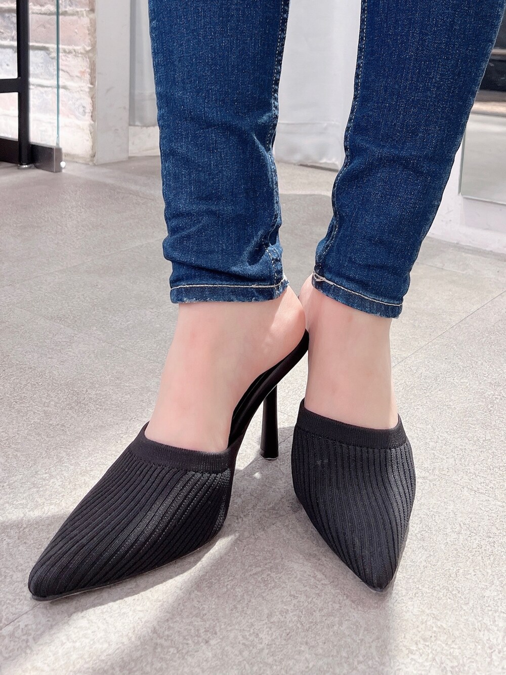 ホワイト系のスウェット、ブルー系のデニムパンツ、ブラック系のパンプスを着用したレディースの冬コーディネートの4枚目の写真