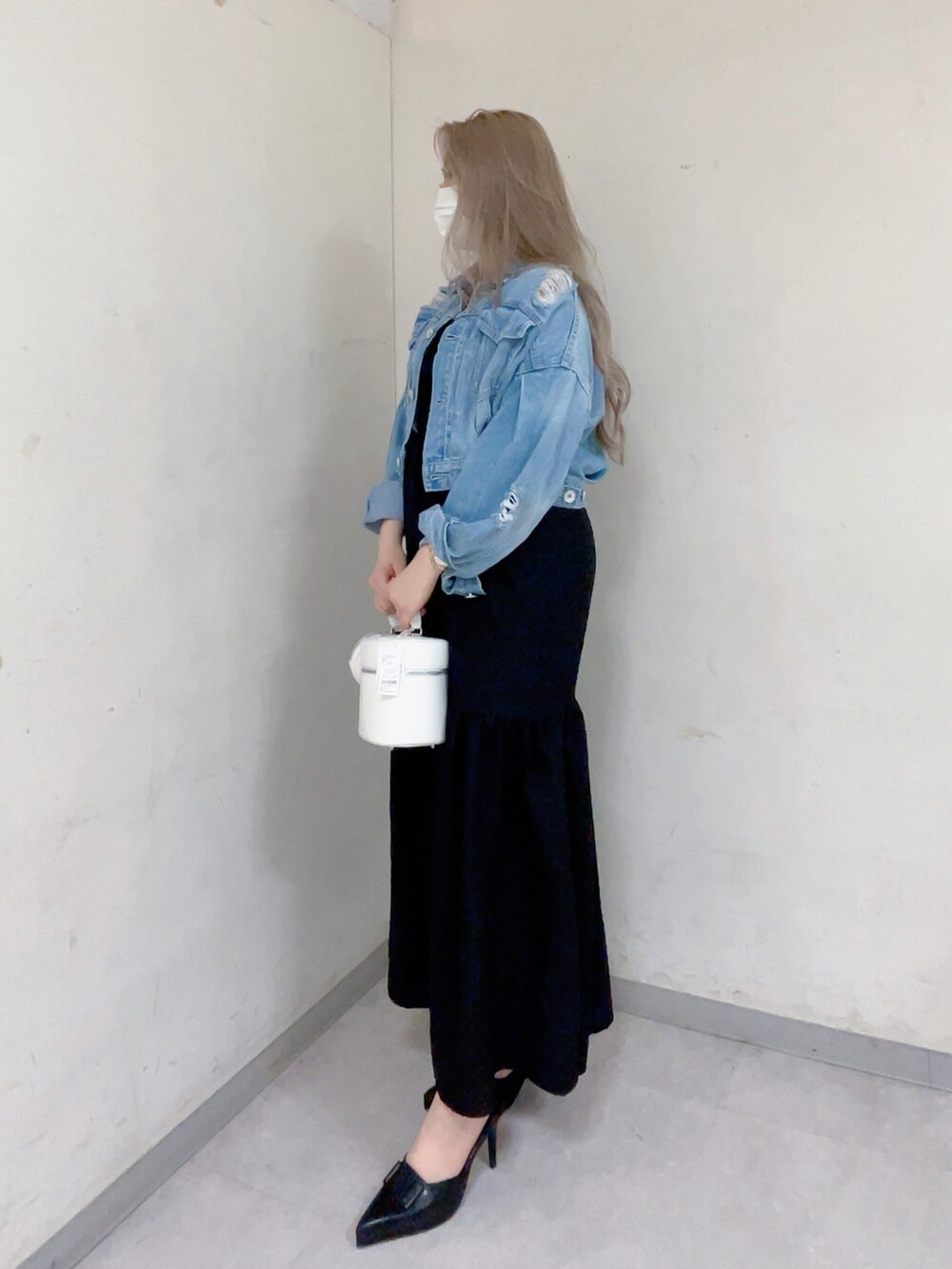 ブルー系のデニムジャケット、ブラック系のワンピース、ホワイト系のハンドバッグを着用したレディースの春コーディネートの3枚目の写真
