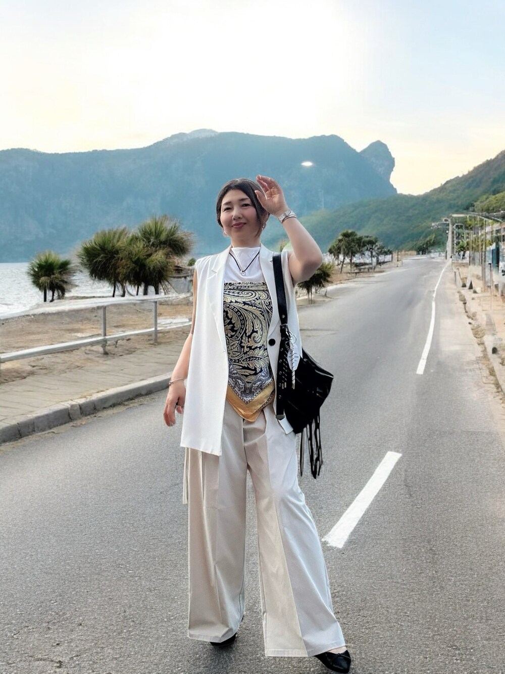 ブラック系のショルダーバッグ、ホワイト系のスラックス、ブラック系のパンプスを着用したレディースの夏コーディネートの2枚目の写真