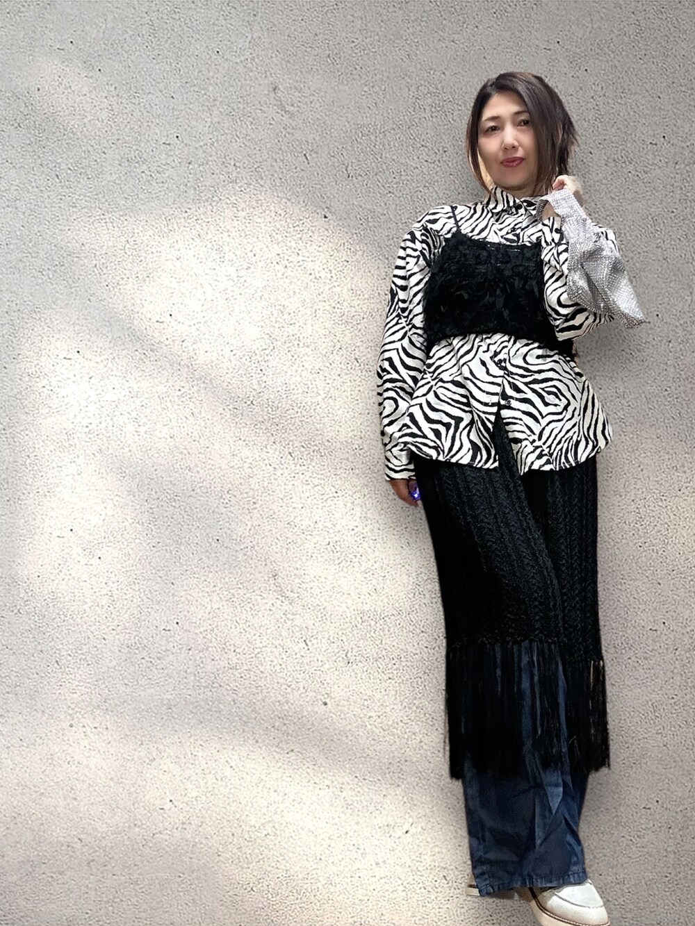 ブラック系のキャミソール、ブラック系のスカート、ブルー系のデニムパンツを着用したレディースの春コーディネートの2枚目の写真