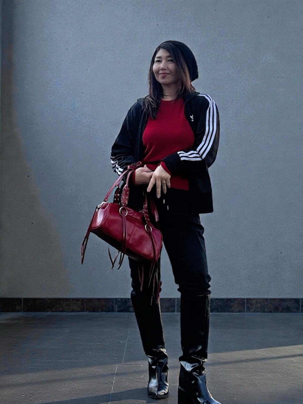 ブラック系のナイロンジャケット、レッド系のニット/セーター、ブラック系のベストを着用したレディースの冬コーディネートの2枚目の写真