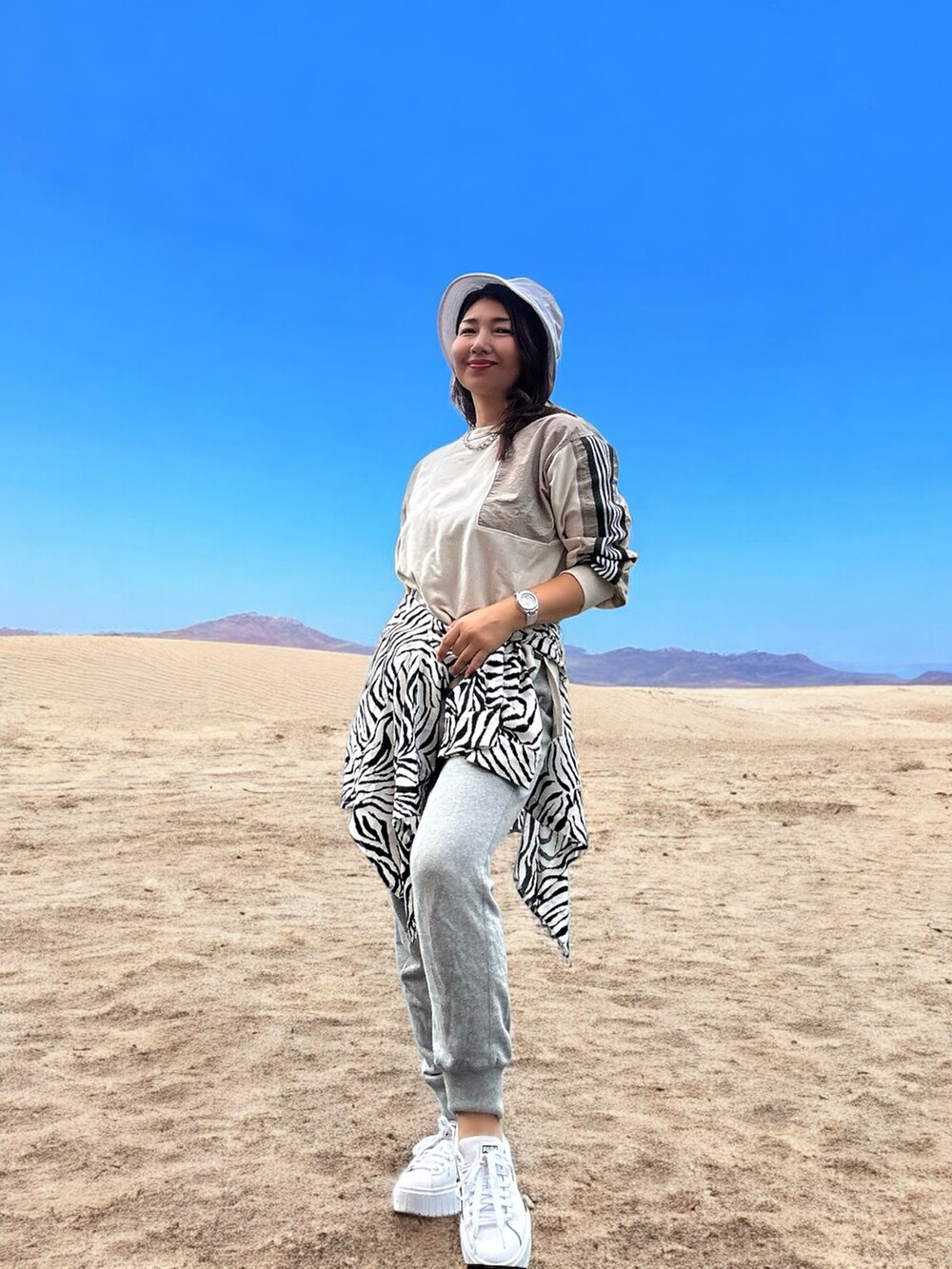 ホワイト系のスニーカー、ベージュ系のトートバッグ、ベージュ系のトップスを着用したレディースの春コーディネートの4枚目の写真