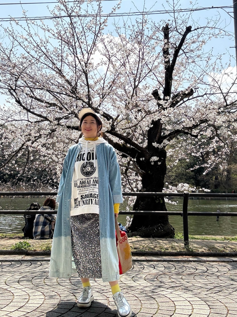 ホワイト系のベスト、シルバー系のスニーカー、レッド系のトートバッグを着用したレディースの春コーディネートの2枚目の写真