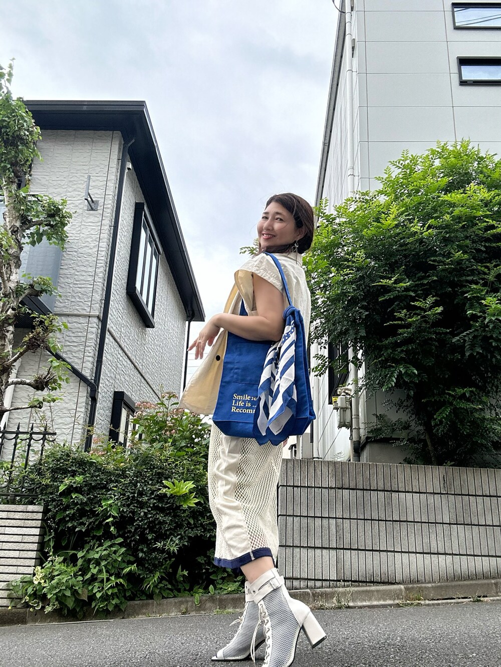 ホワイト系のブーツ、ホワイト系のベスト、ブルー系のトートバッグを着用したレディースの夏コーディネートの5枚目の写真