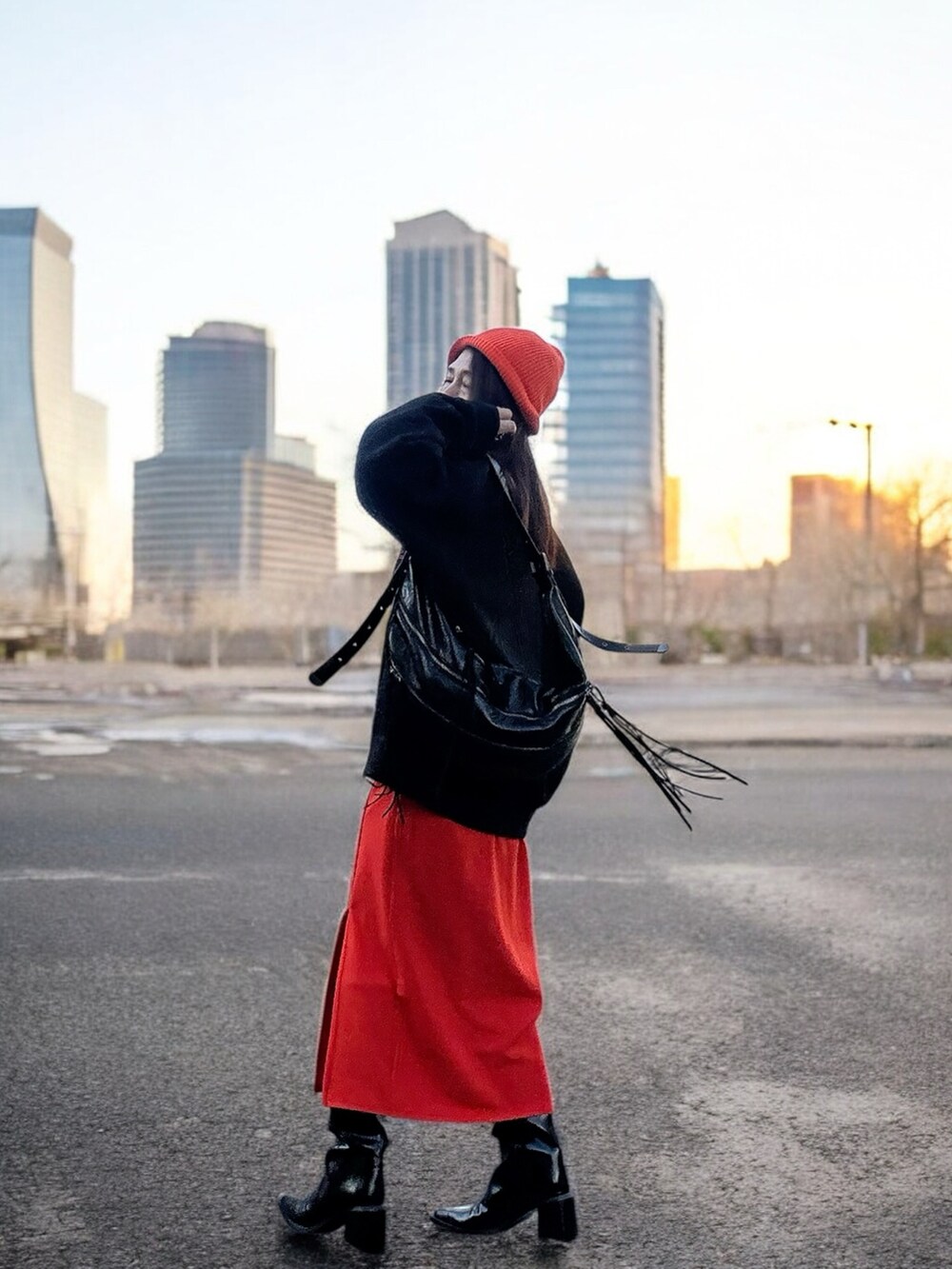 ブラック系のショルダーバッグ、ブラック系のスウェット、オレンジ系のスカートを着用したレディースの冬コーディネートの2枚目の写真