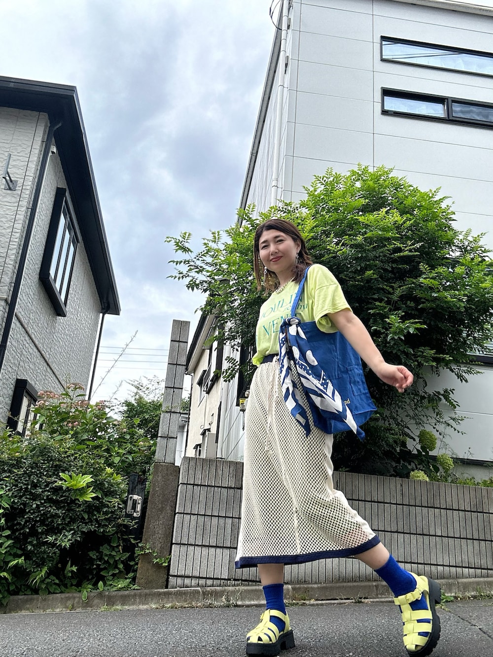 イエロー系のTシャツ/カットソー、ベージュ系のスカート、グリーン系のサンダルを着用したレディースの夏コーディネートの3枚目の写真