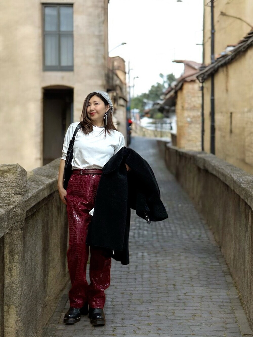 ブラック系のムートンコート、ブラック系のショルダーバッグ、ブラック系のブーツを着用したレディースの秋コーディネートの3枚目の写真