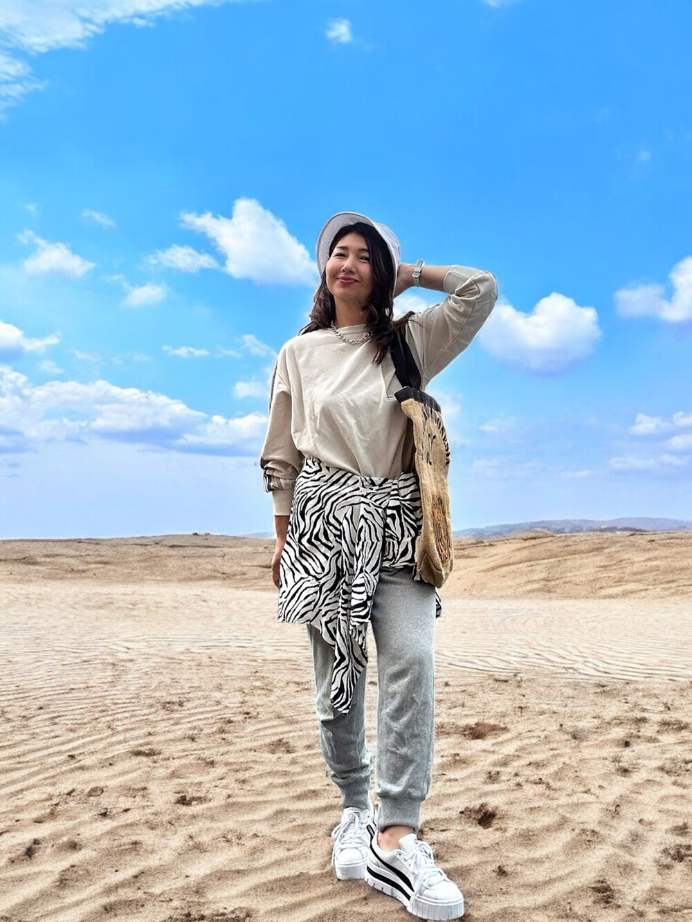 ホワイト系のスニーカー、ベージュ系のトートバッグ、ベージュ系のトップスを着用したレディースの春コーディネートの3枚目の写真