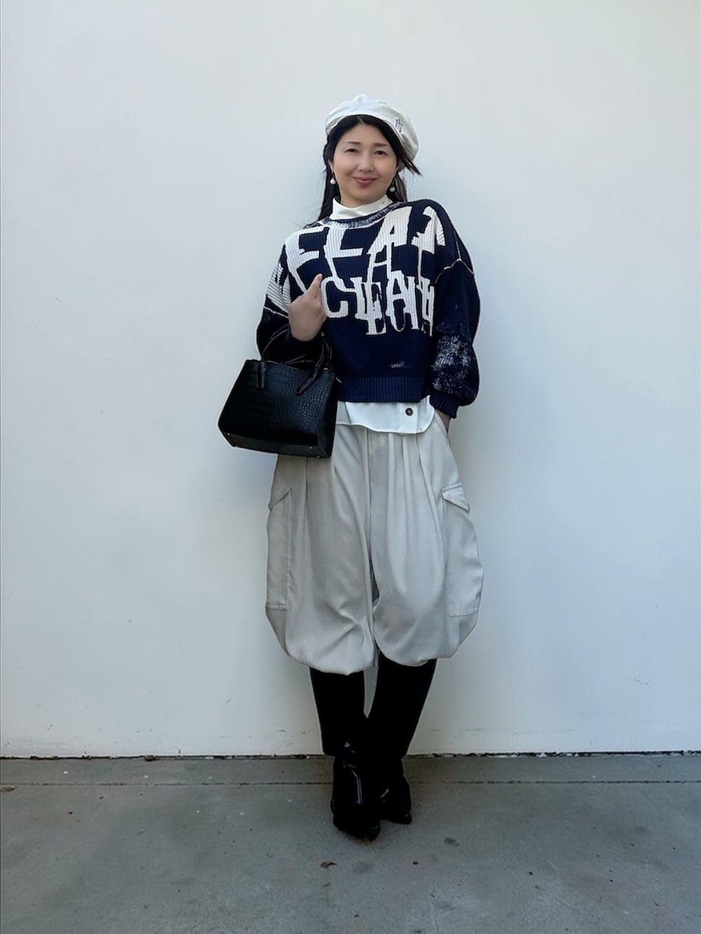 ブルー系のニット/セーター、ホワイト系のカーゴパンツ、ブラック系のブーツを着用したレディースの春コーディネートの2枚目の写真