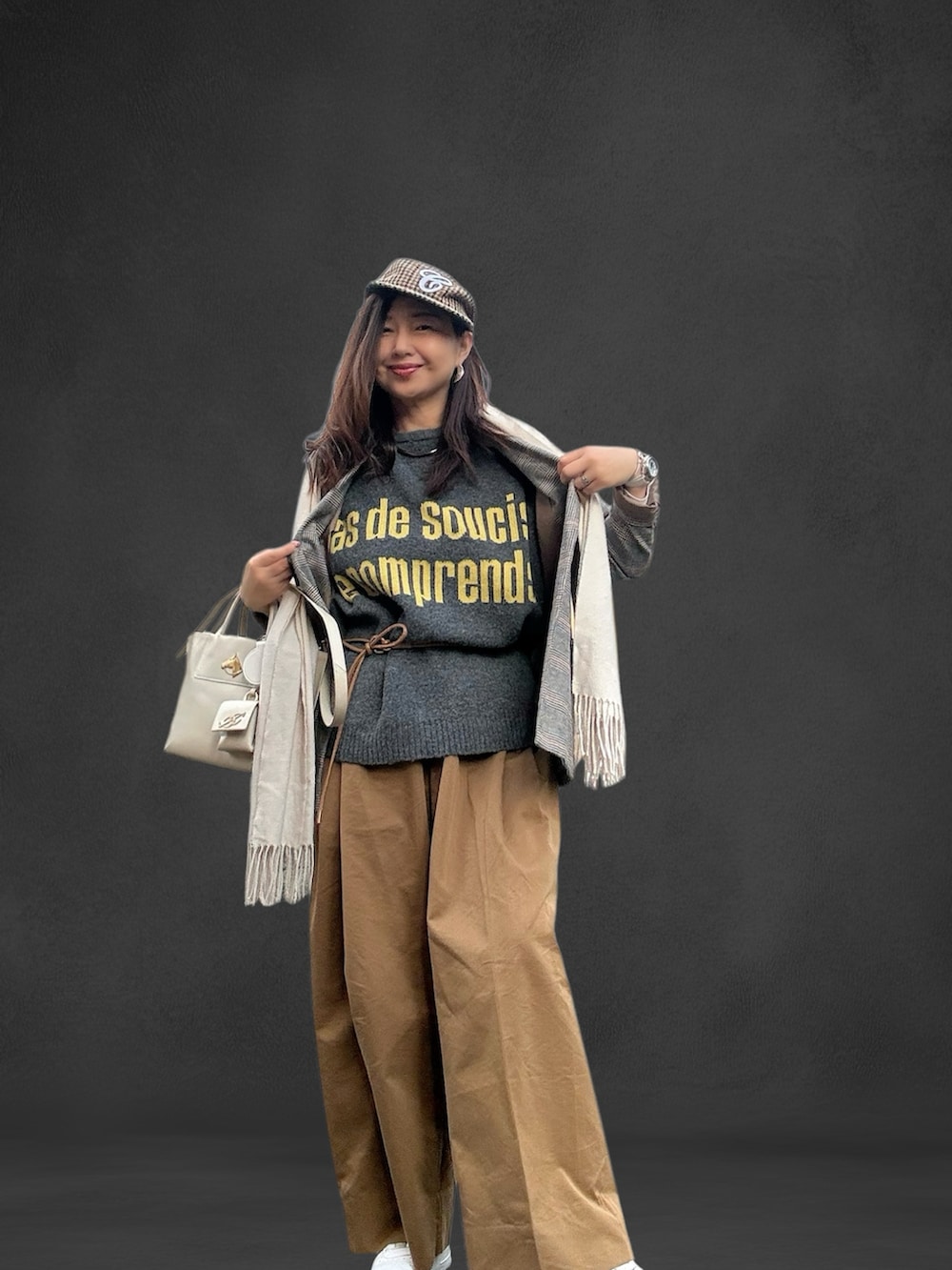 ホワイト系のトートバッグ、ホワイト系のスニーカー、グレー系のニット/セーターを着用したレディースの冬コーディネートの2枚目の写真