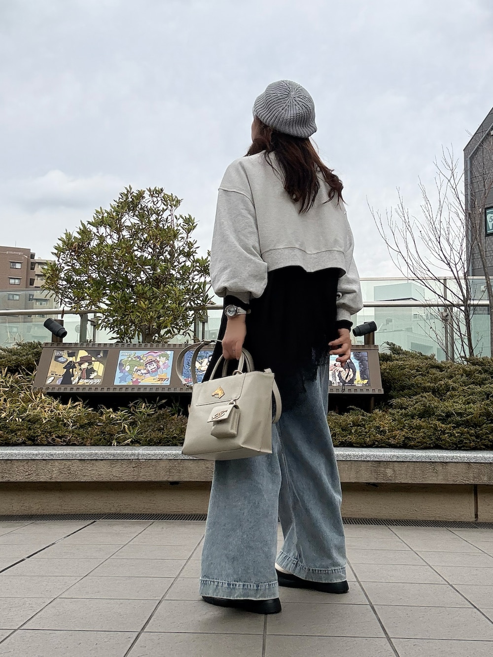 ホワイト系のトートバッグ、ホワイト系のブーツ、ブルー系のデニムパンツを着用したレディースの春コーディネートの3枚目の写真