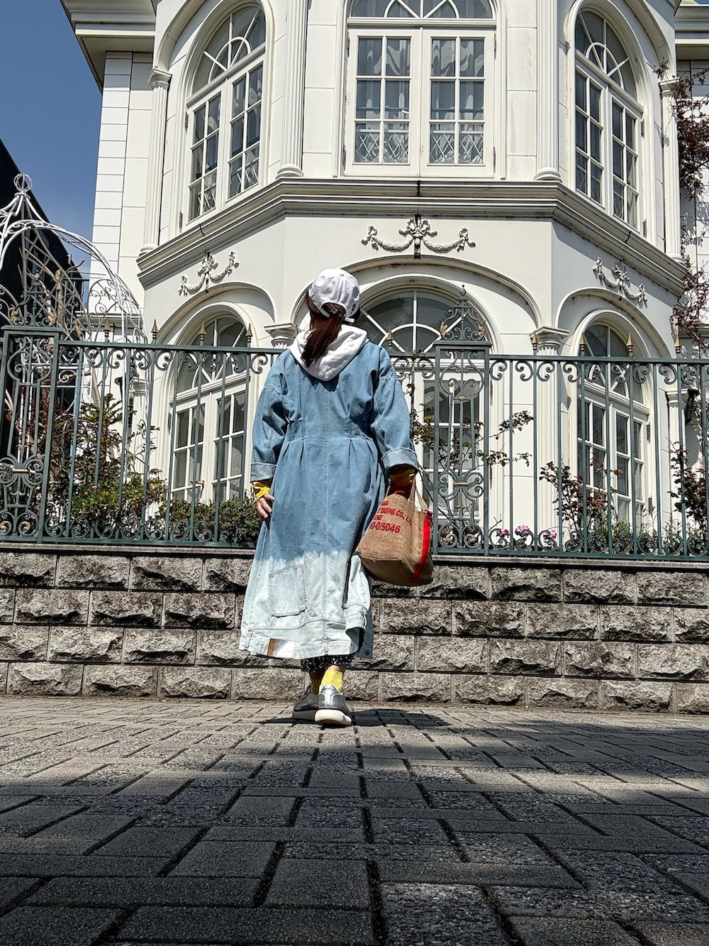 ホワイト系のベスト、シルバー系のスニーカー、レッド系のトートバッグを着用したレディースの春コーディネートの4枚目の写真