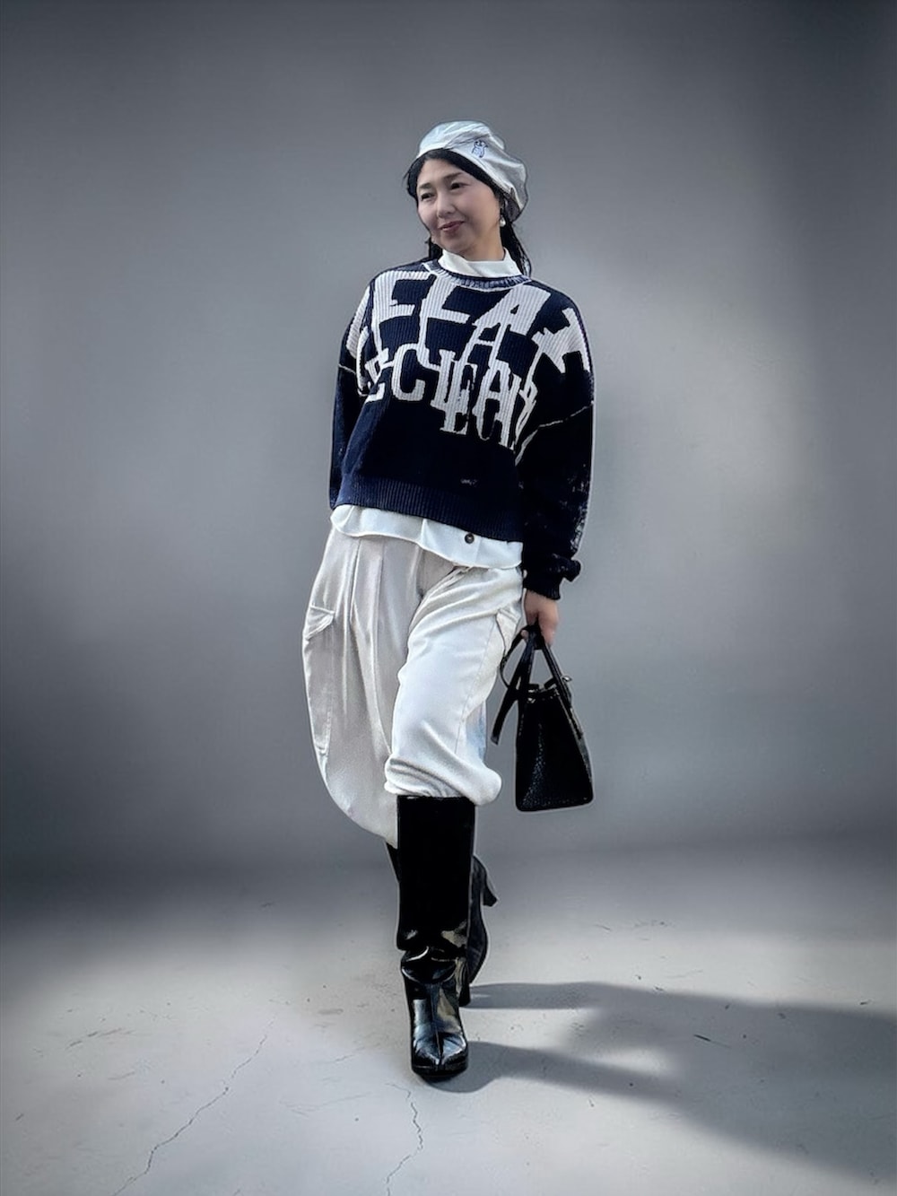 ブルー系のニット/セーター、ホワイト系のカーゴパンツ、ブラック系のブーツを着用したレディースの春コーディネートの3枚目の写真