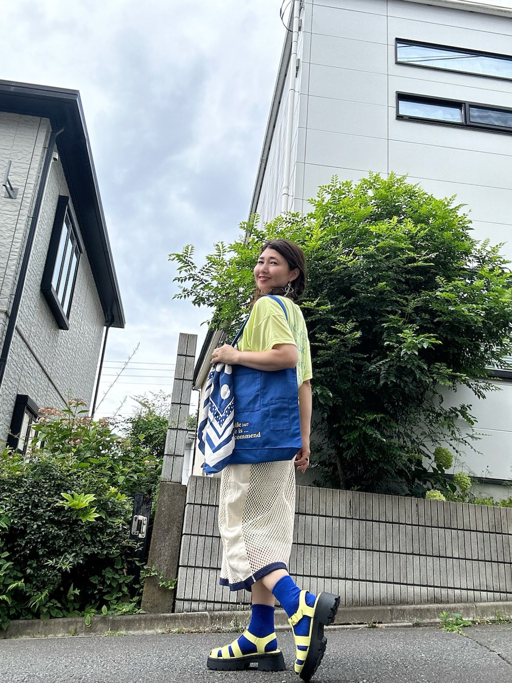 イエロー系のTシャツ/カットソー、ベージュ系のスカート、グリーン系のサンダルを着用したレディースの夏コーディネートの2枚目の写真