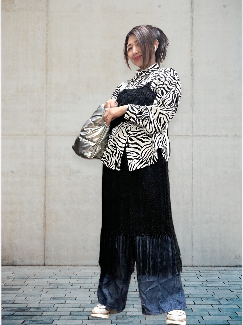 ブラック系のキャミソール、ブラック系のスカート、ブルー系のデニムパンツを着用したレディースの春コーディネートの3枚目の写真