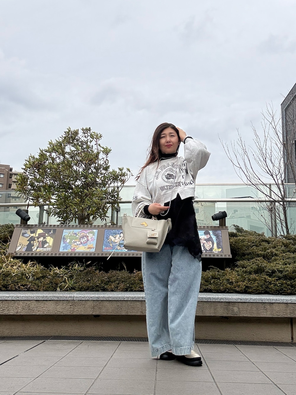 ホワイト系のトートバッグ、ホワイト系のブーツ、ブルー系のデニムパンツを着用したレディースの春コーディネートの2枚目の写真