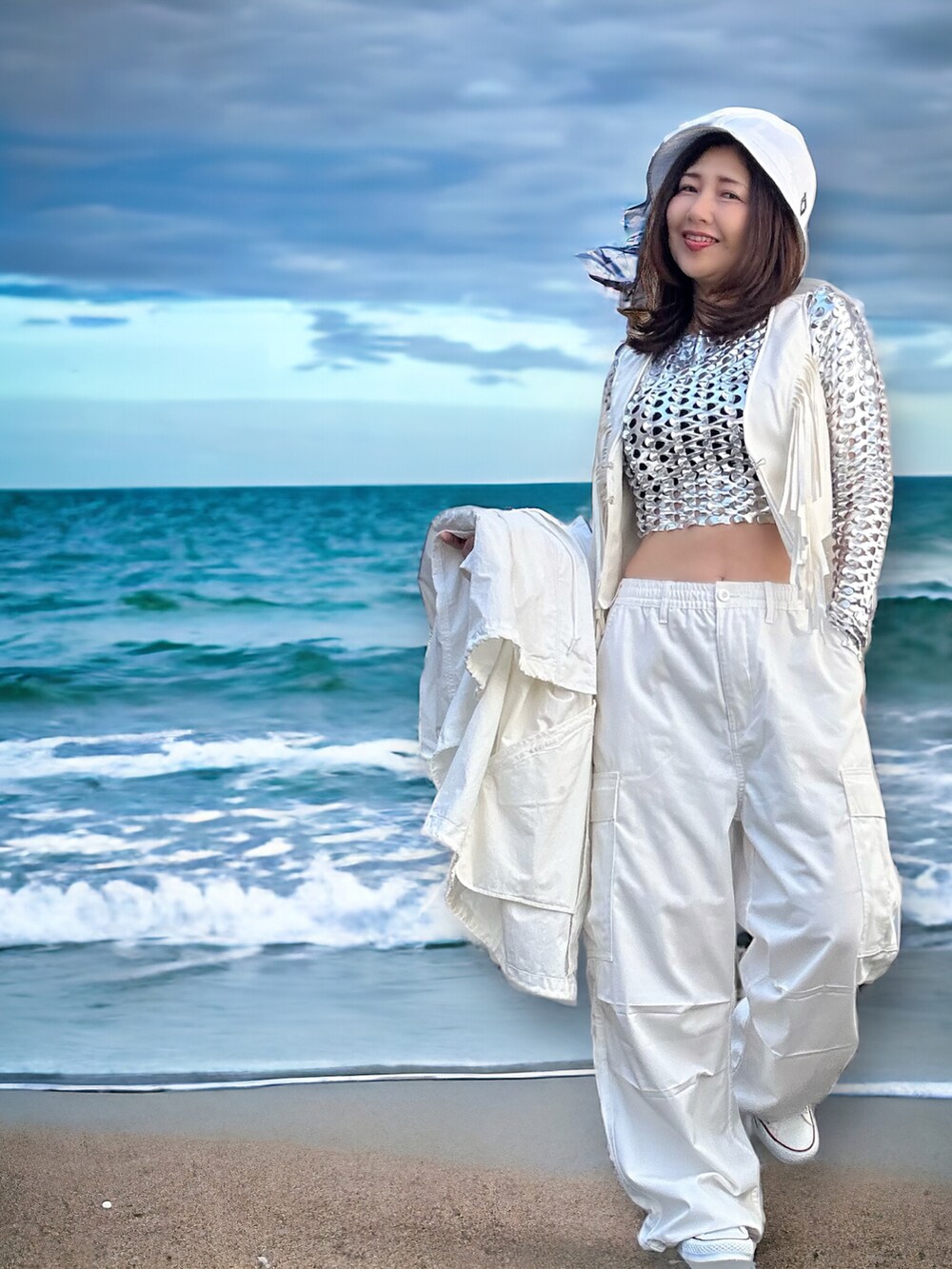 シルバー系のトップス、ホワイト系のベスト、ホワイト系のダウンベストを着用したレディースの春コーディネートの3枚目の写真