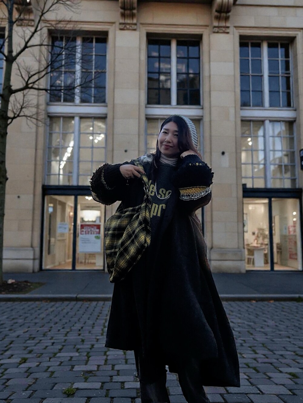 イエロー系のスニーカー、ブラック系のその他アウター、グレー系のニット/セーターを着用したレディースの冬コーディネートの2枚目の写真