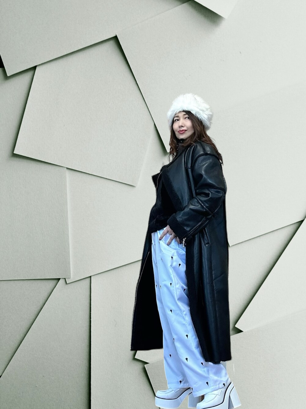 ブラック系のムートンコート、ブラック系のベスト、ホワイト系のドレスシューズを着用したレディースの春コーディネートの2枚目の写真