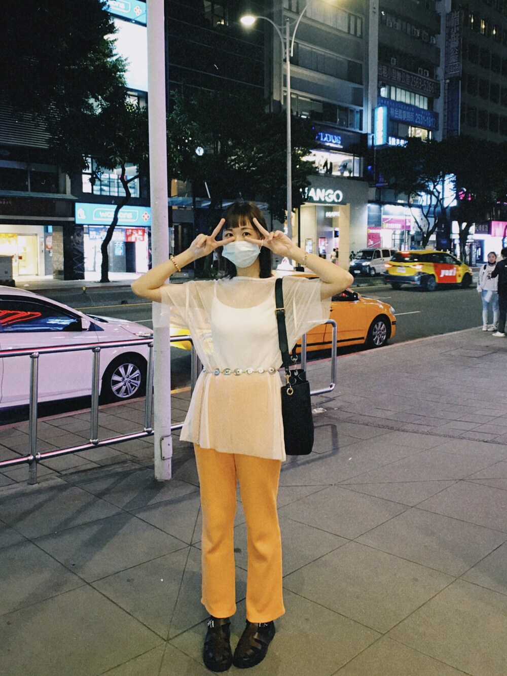 ブラウン系のサンダル、オレンジ系のチノパンツ、ブラック系のショルダーバッグを着用したレディースの秋コーディネートの2枚目の写真