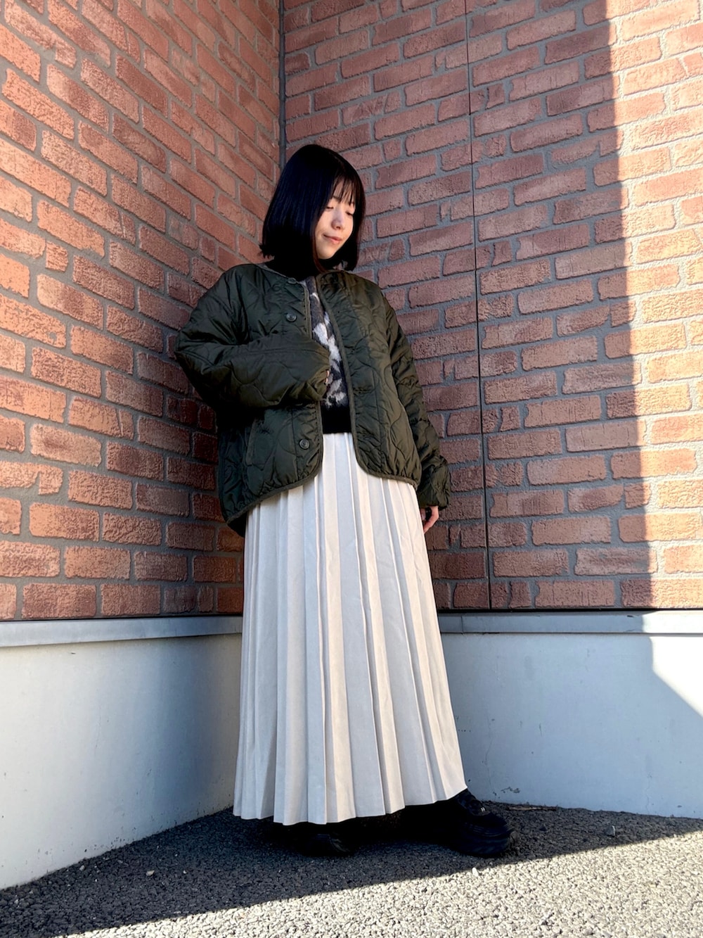 グリーン系のブルゾン、ベージュ系のスカート、ブラウン系のニット/セーターを着用したレディースの冬コーディネートの2枚目の写真