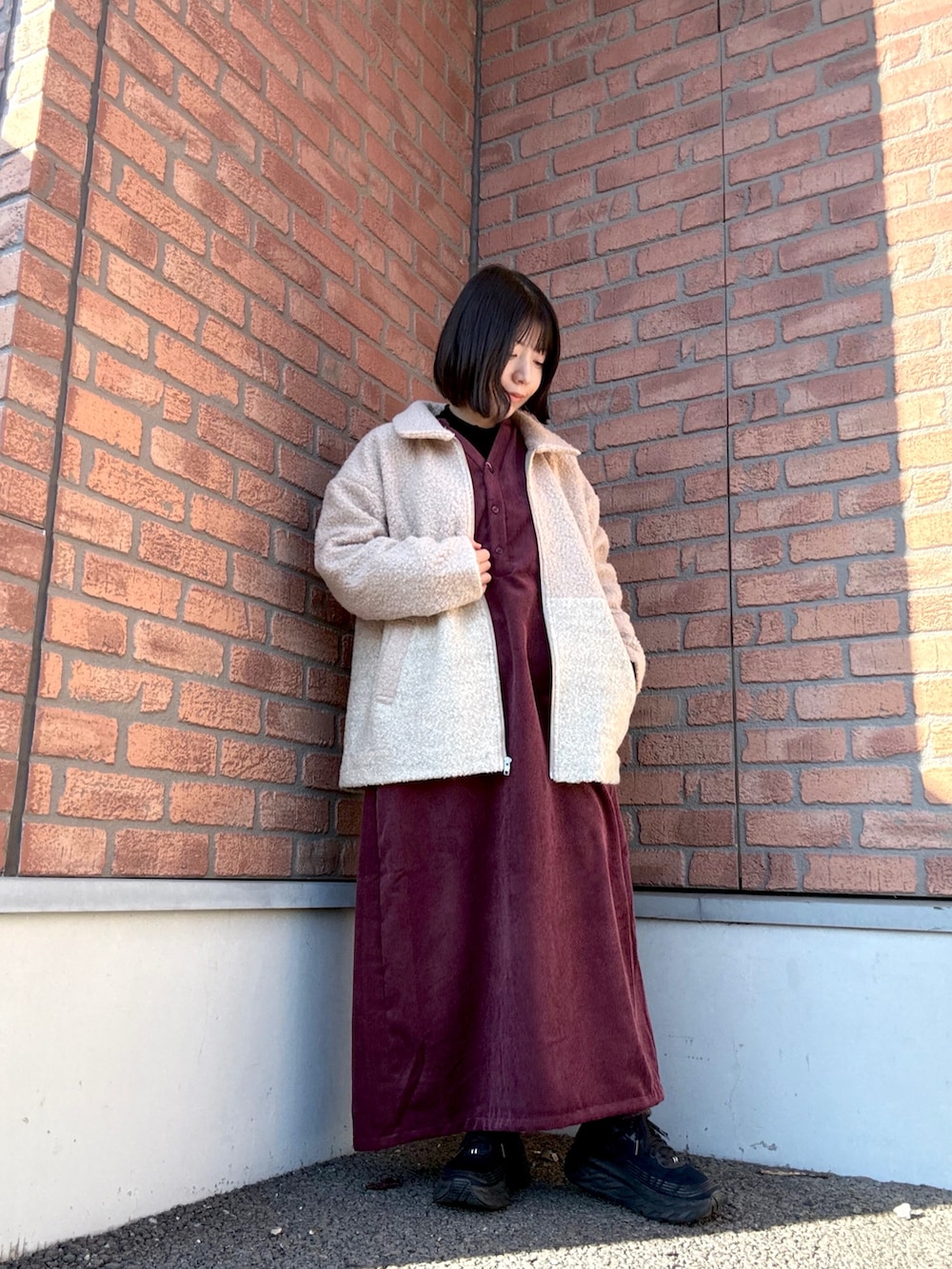 パープル系のテーラードジャケット、レッド系のワンピースを着用したレディースの冬コーディネートの2枚目の写真