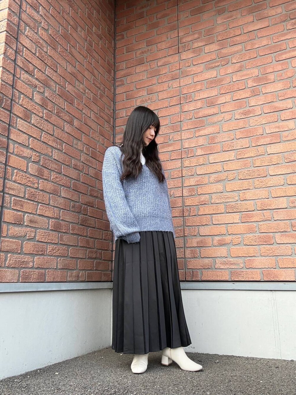 ブルー系のニット/セーター、ホワイト系のTシャツ/カットソー、ブラック系のスカートを着用したレディースの冬コーディネートの2枚目の写真