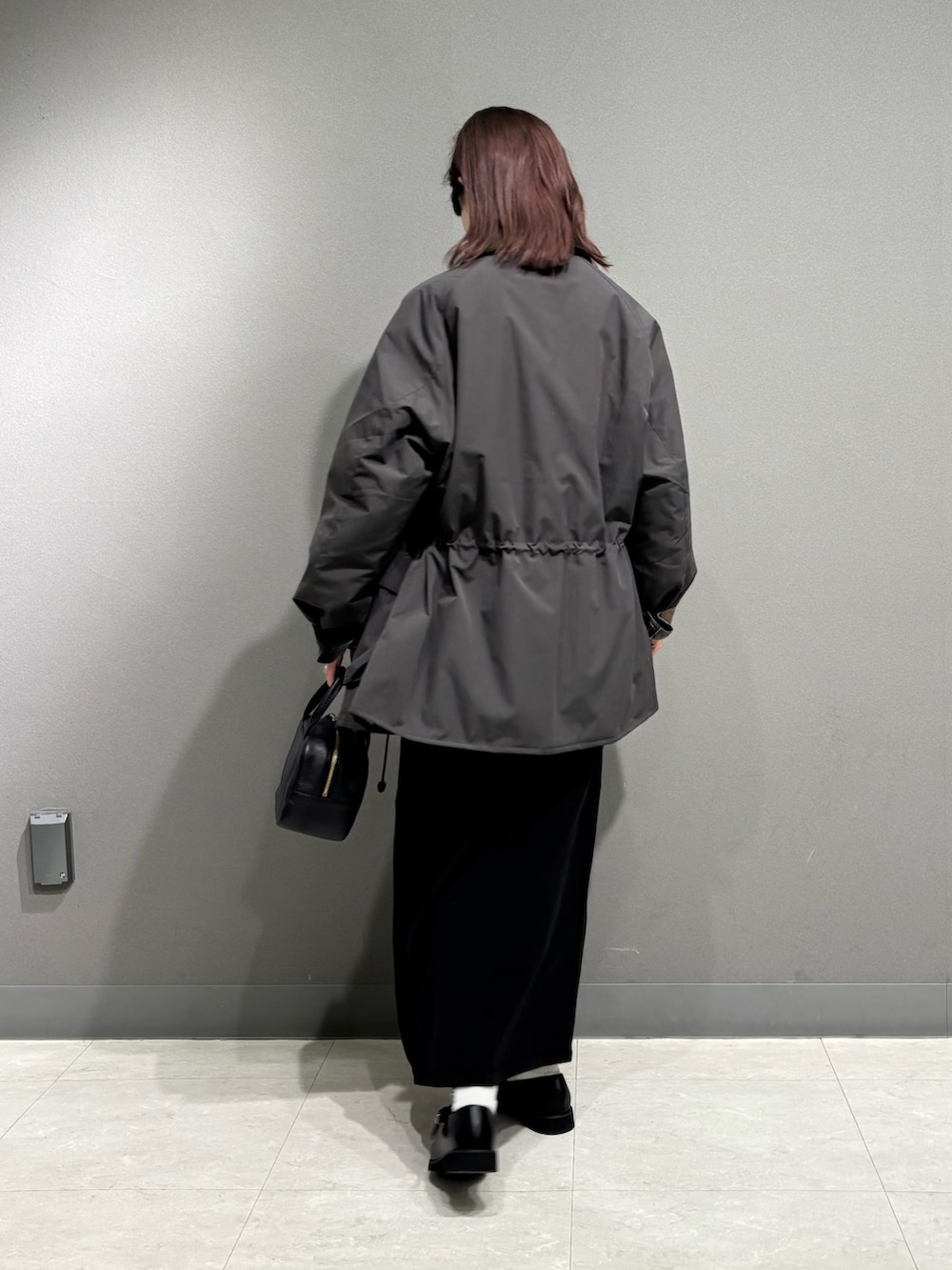 グレー系のその他アウター、ブラック系のローファー、ブラック系のスカートを着用したレディースの秋コーディネートの5枚目の写真