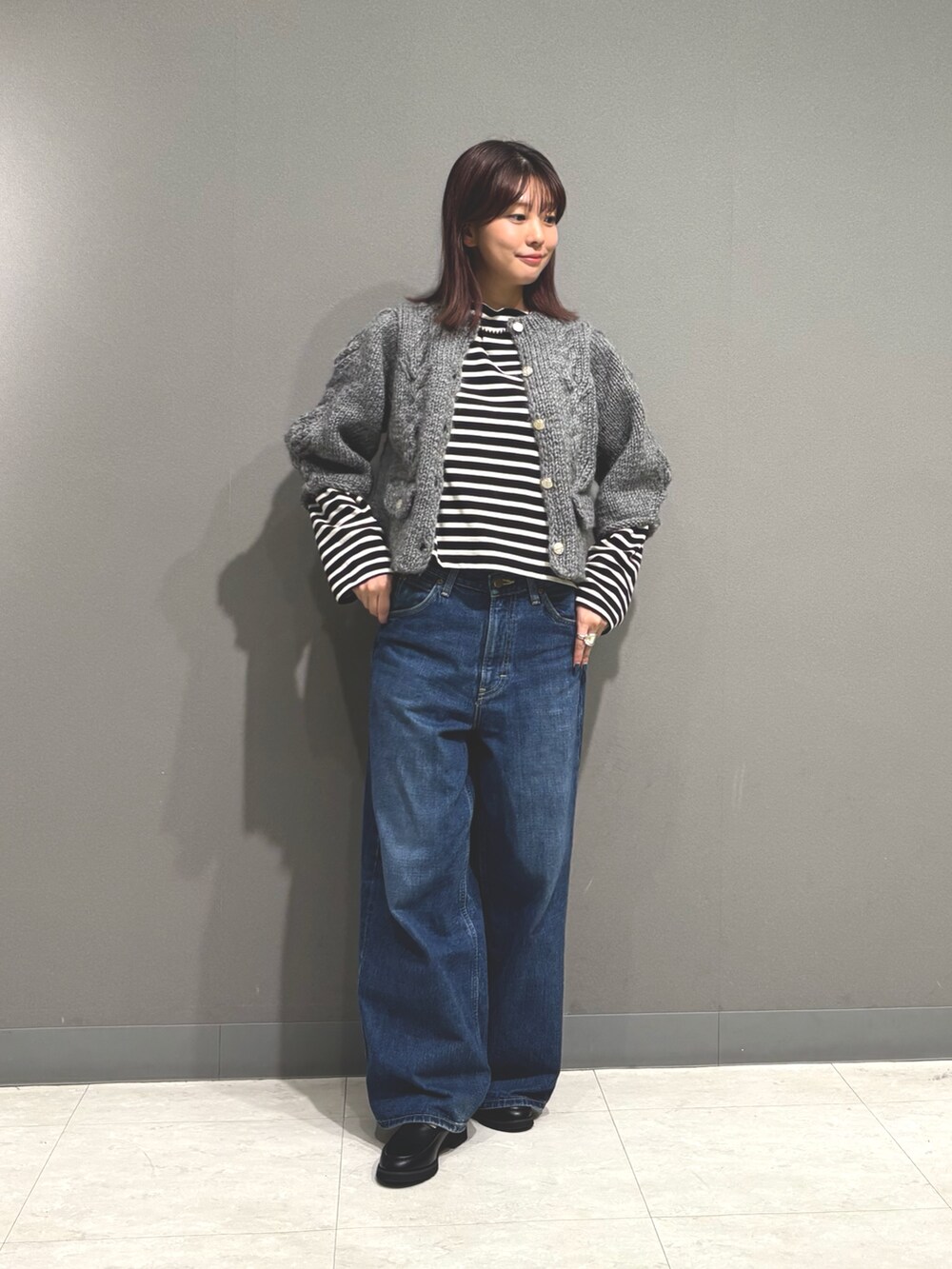 ブルー系のデニムパンツ、グレー系のカーディガン/ボレロ、ブラック系のTシャツ/カットソーを着用したレディースの秋コーディネートの2枚目の写真