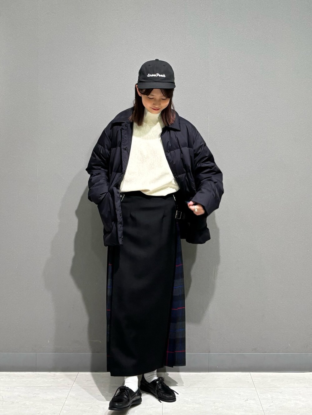 グレー系のスカート、ブラック系のダウンジャケット/コート、ベージュ系のスウェットを着用したレディースの秋コーディネートの5枚目の写真