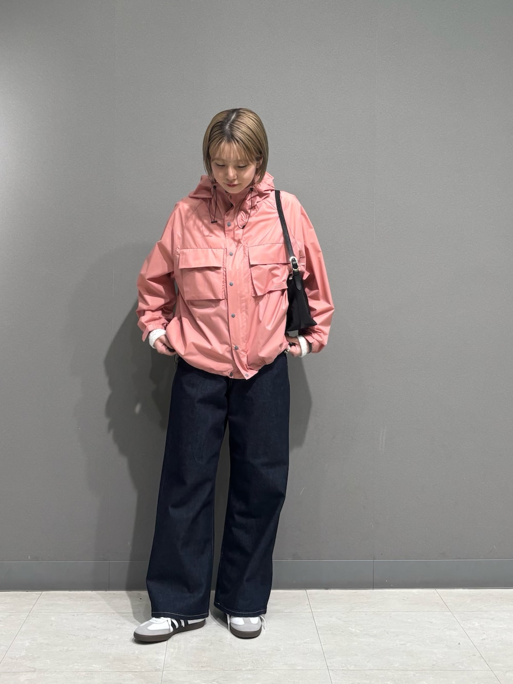 ピンク系のナイロンジャケット、ブルー系のデニムパンツ、ホワイト系のスニーカーを着用したレディースの冬コーディネートの4枚目の写真