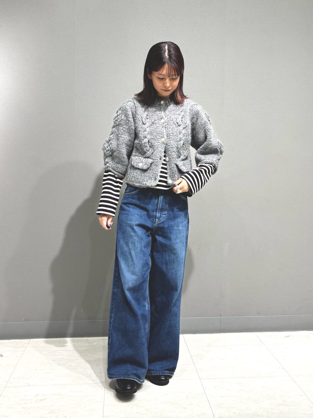 ブルー系のデニムパンツ、グレー系のカーディガン/ボレロ、ブラック系のTシャツ/カットソーを着用したレディースの秋コーディネートの3枚目の写真