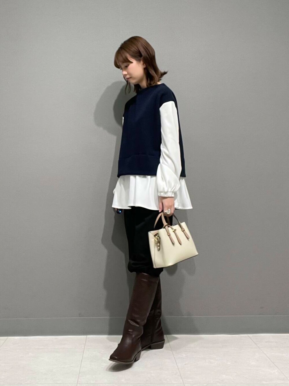 ホワイト系のハンドバッグ、ブラウン系のブーツ、ブラック系のその他パンツを着用したレディースの冬コーディネートの4枚目の写真