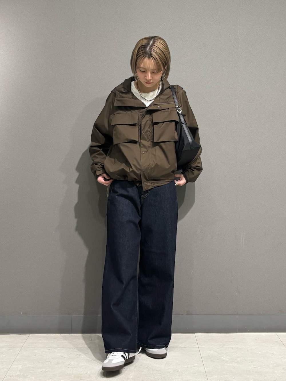 ブラウン系のナイロンジャケット、ブルー系のデニムパンツ、ホワイト系のスニーカーを着用したレディースの冬コーディネートの2枚目の写真