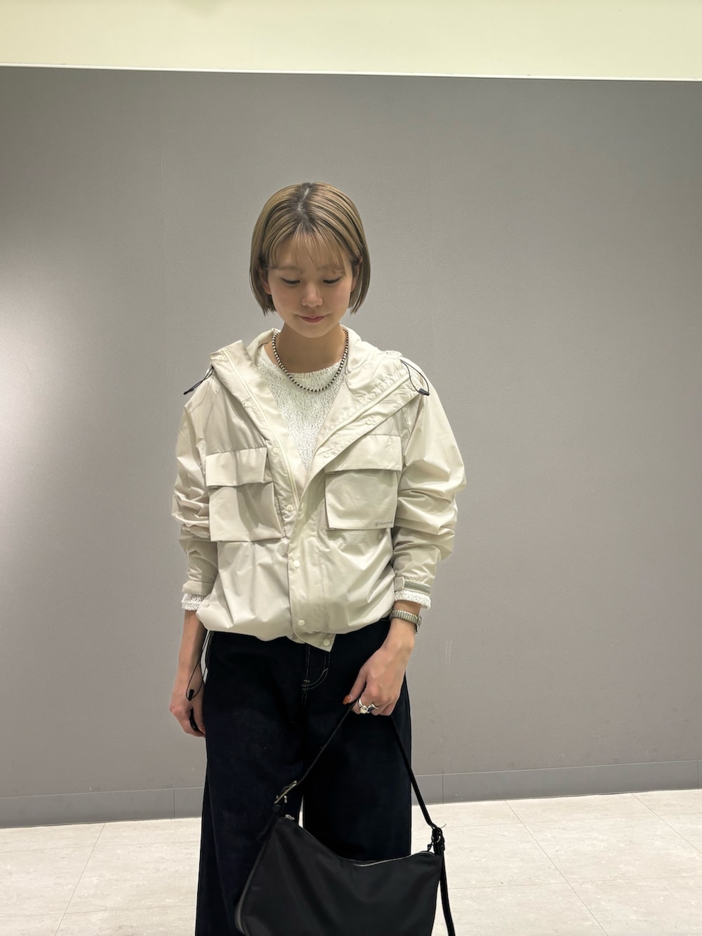 ホワイト系のナイロンジャケット、ブルー系のデニムパンツ、ブラック系のショルダーバッグを着用したレディースの冬コーディネートの3枚目の写真