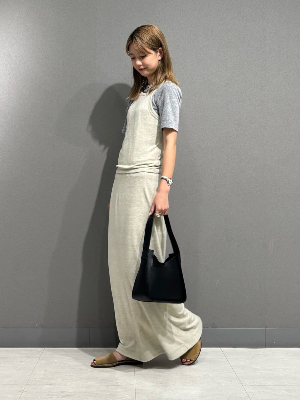 グレー系のTシャツ/カットソー、グレー系のスカート、ブラック系のハンドバッグを着用したレディースの秋コーディネートの5枚目の写真