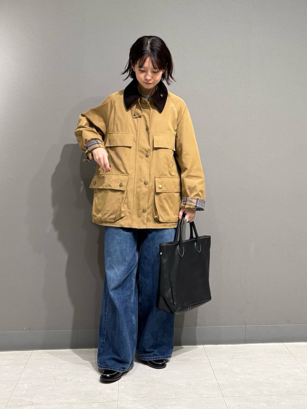 ベージュ系のテーラードジャケット、ブラック系のトートバッグ、ブルー系のデニムパンツを着用したレディースの秋コーディネートの7枚目の写真