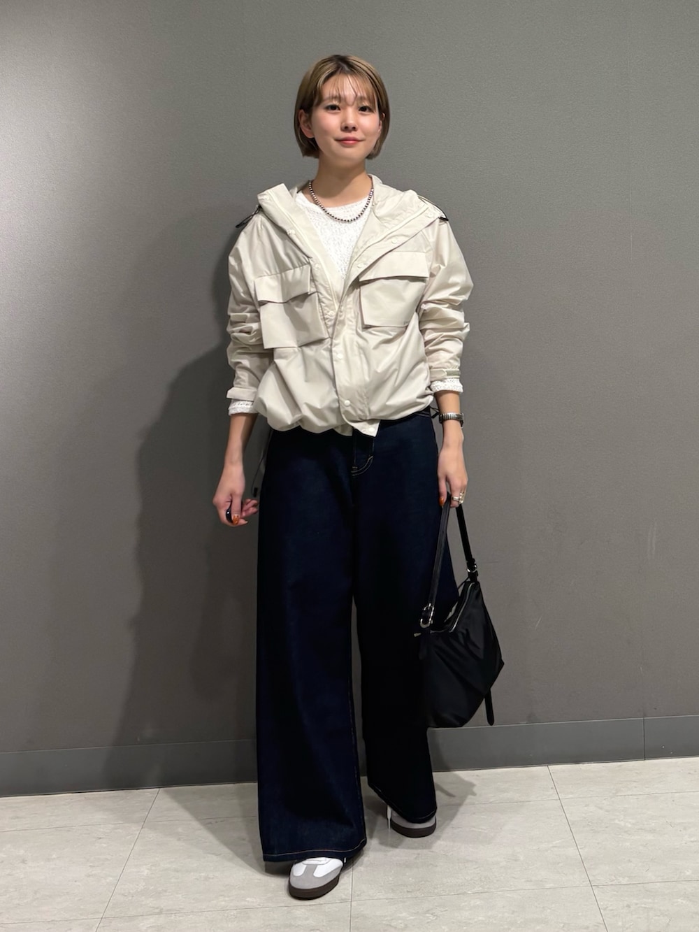 ホワイト系のナイロンジャケット、ブルー系のデニムパンツ、ブラック系のショルダーバッグを着用したレディースの冬コーディネートの4枚目の写真