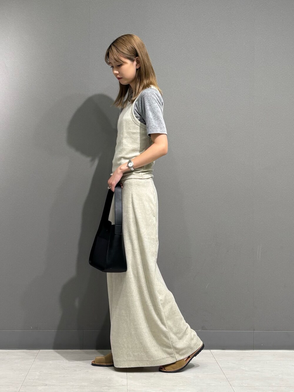 グレー系のTシャツ/カットソー、グレー系のスカート、ブラック系のハンドバッグを着用したレディースの秋コーディネートの3枚目の写真