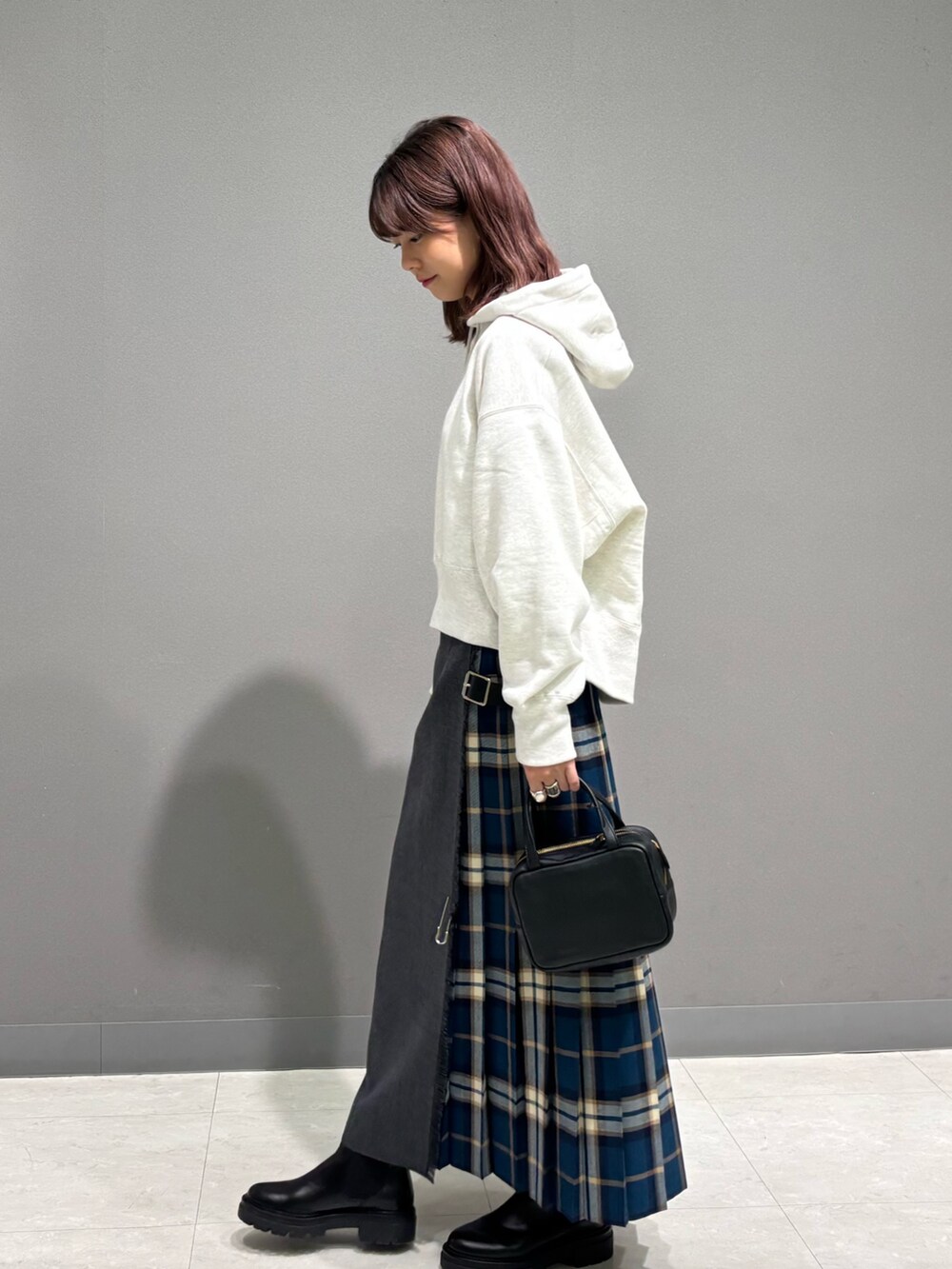 グリーン系のスカート、ブラック系のブーツ、ベージュ系のパーカーを着用したレディースの秋コーディネートの4枚目の写真