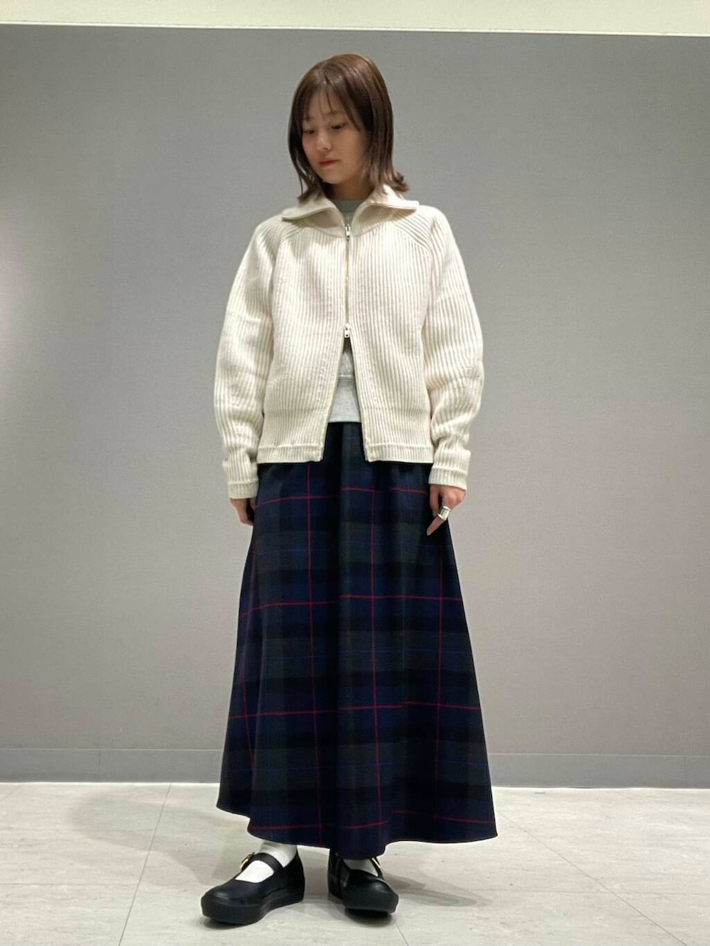 ホワイト系のカーディガン/ボレロ、グレー系のTシャツ/カットソー、ブルー系のスカートを着用したレディースの秋コーディネートの7枚目の写真