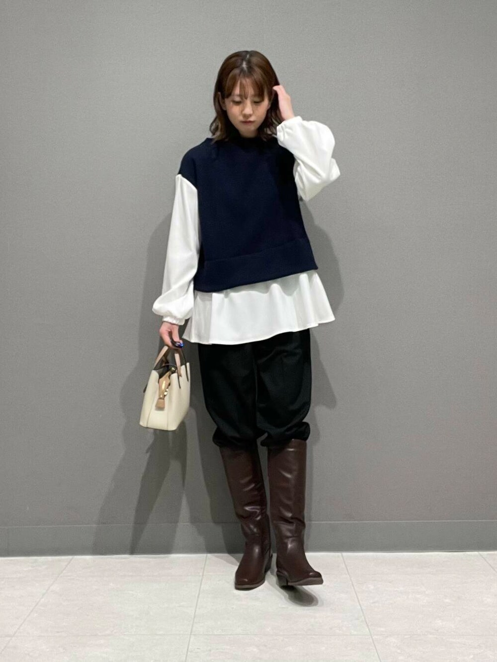 ホワイト系のハンドバッグ、ブラウン系のブーツ、ブラック系のその他パンツを着用したレディースの冬コーディネートの2枚目の写真