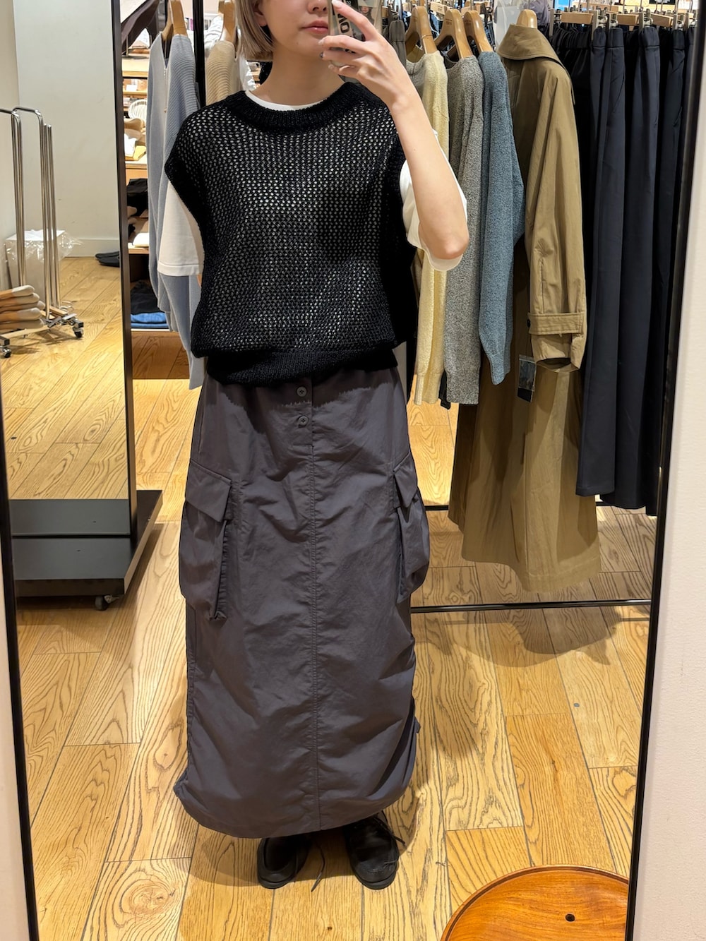 グレー系のTシャツ/カットソー、ブラック系のベスト、グレー系のスカートを着用したレディースの春コーディネートの2枚目の写真