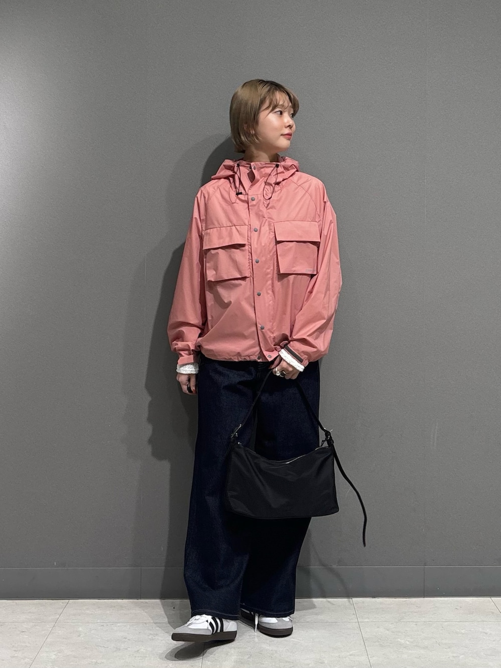 ピンク系のナイロンジャケット、ブルー系のデニムパンツ、ホワイト系のスニーカーを着用したレディースの冬コーディネートの5枚目の写真