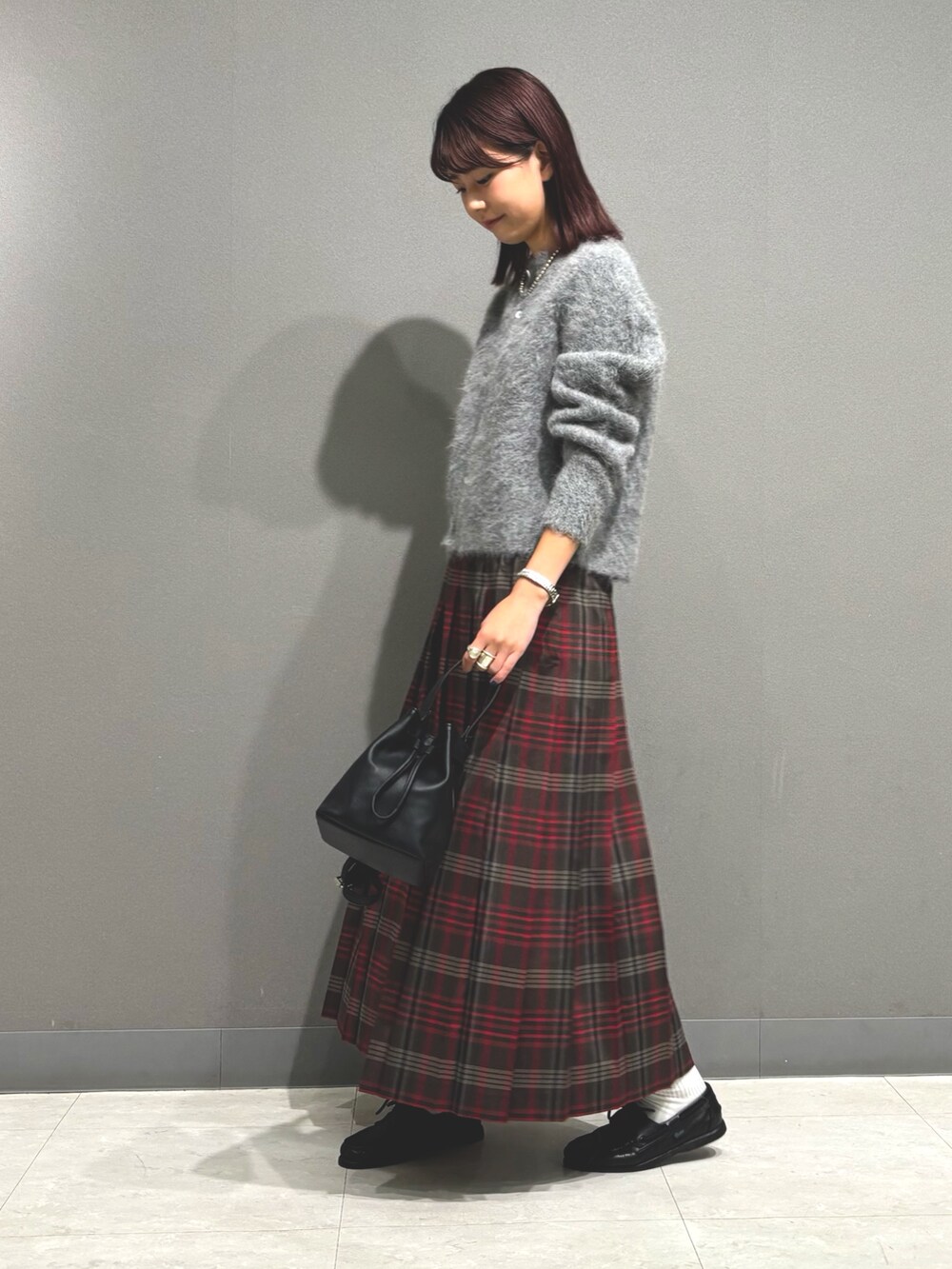 ブラウン系のスカート、グレー系のカーディガン/ボレロ、ブラック系のショルダーバッグを着用したレディースの秋コーディネートの3枚目の写真