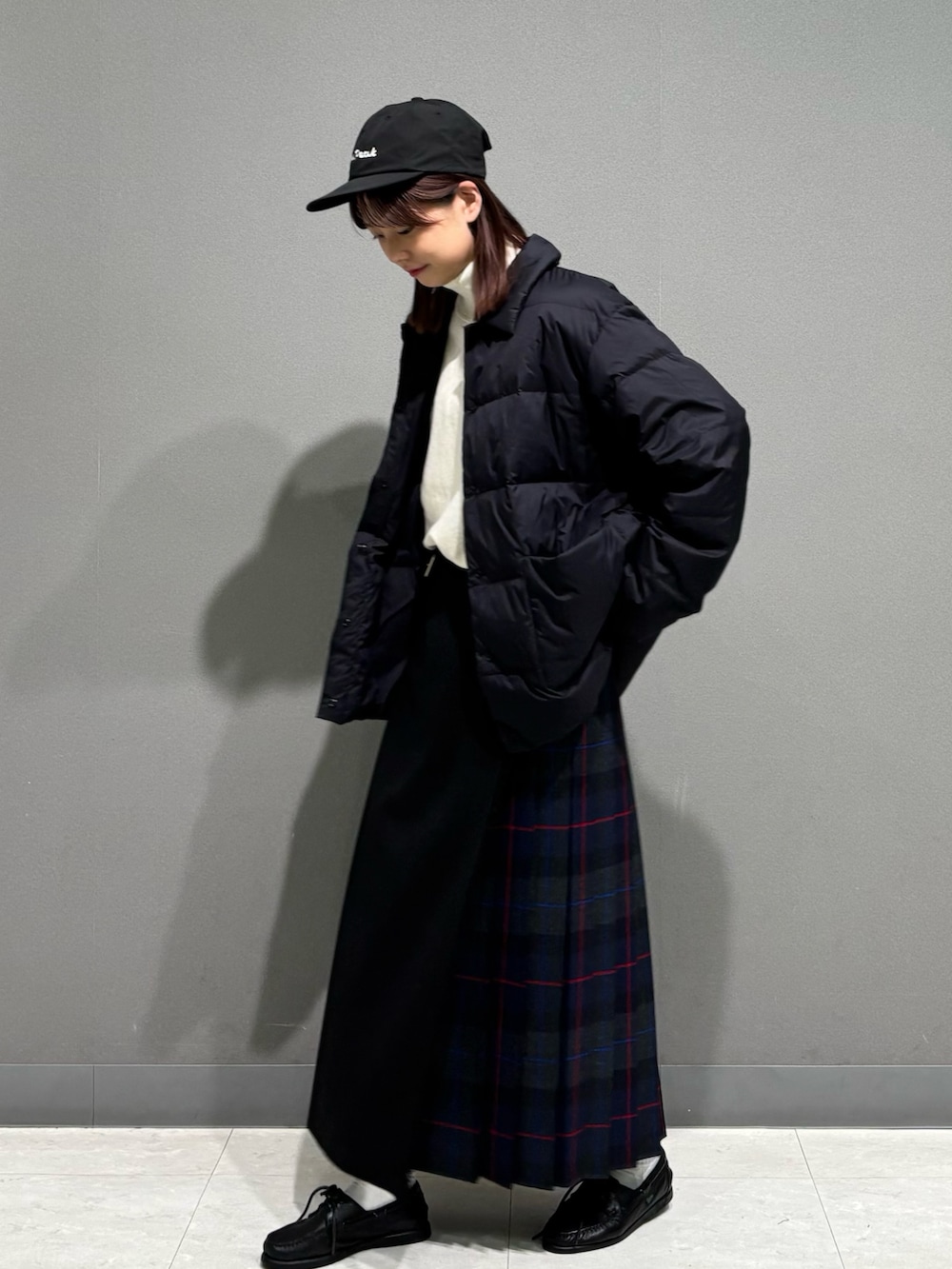 グレー系のスカート、ブラック系のダウンジャケット/コート、ベージュ系のスウェットを着用したレディースの秋コーディネートの3枚目の写真