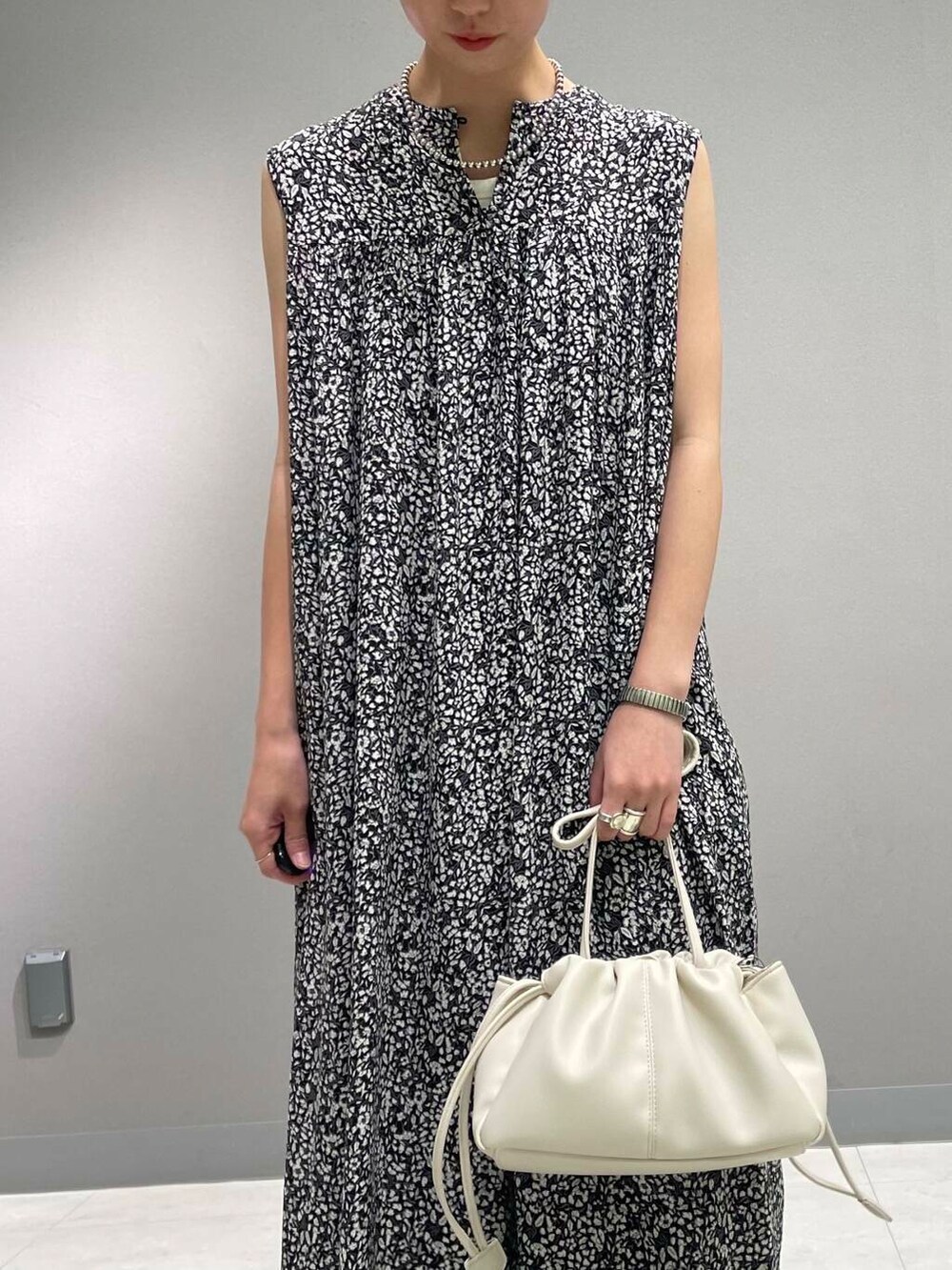 ホワイト系のショルダーバッグ、ブルー系のデニムパンツ、ブラック系のワンピースを着用したレディースの夏コーディネートの7枚目の写真