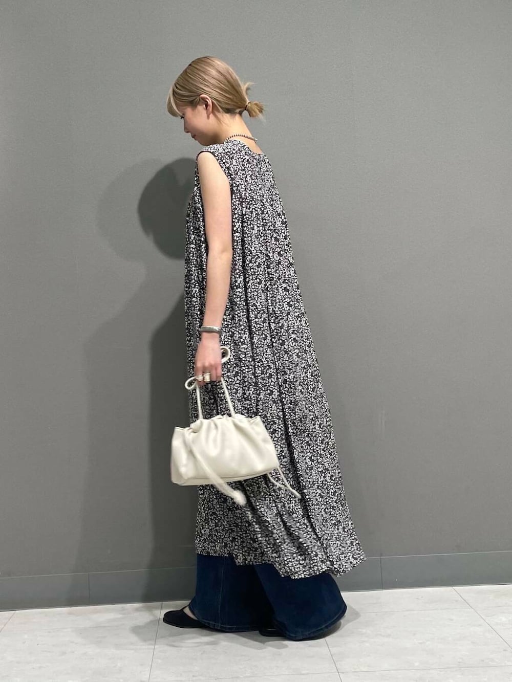 ホワイト系のショルダーバッグ、ブルー系のデニムパンツ、ブラック系のワンピースを着用したレディースの夏コーディネートの3枚目の写真