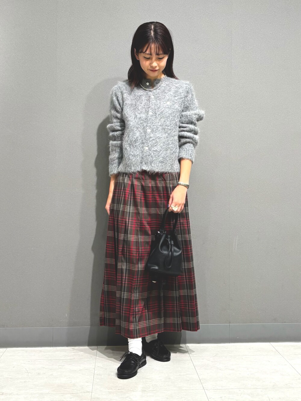 ブラウン系のスカート、グレー系のカーディガン/ボレロ、ブラック系のショルダーバッグを着用したレディースの秋コーディネートの2枚目の写真