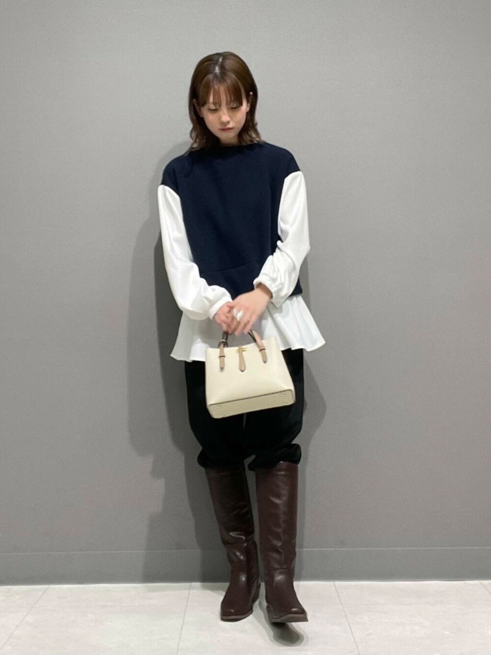 ホワイト系のハンドバッグ、ブラウン系のブーツ、ブラック系のその他パンツを着用したレディースの冬コーディネートの3枚目の写真